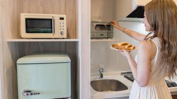 A kitchen with a vintage refrigerator, a microwave, a toaster oven, and a sink.