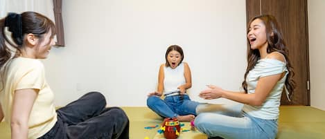 Three people sitting on a mat in a room with a wooden door and a white wall.