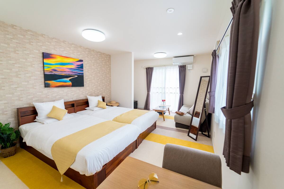Une chambre d’hôtel avec un grand lit, un bureau, une chaise, un miroir et un tableau au mur.
