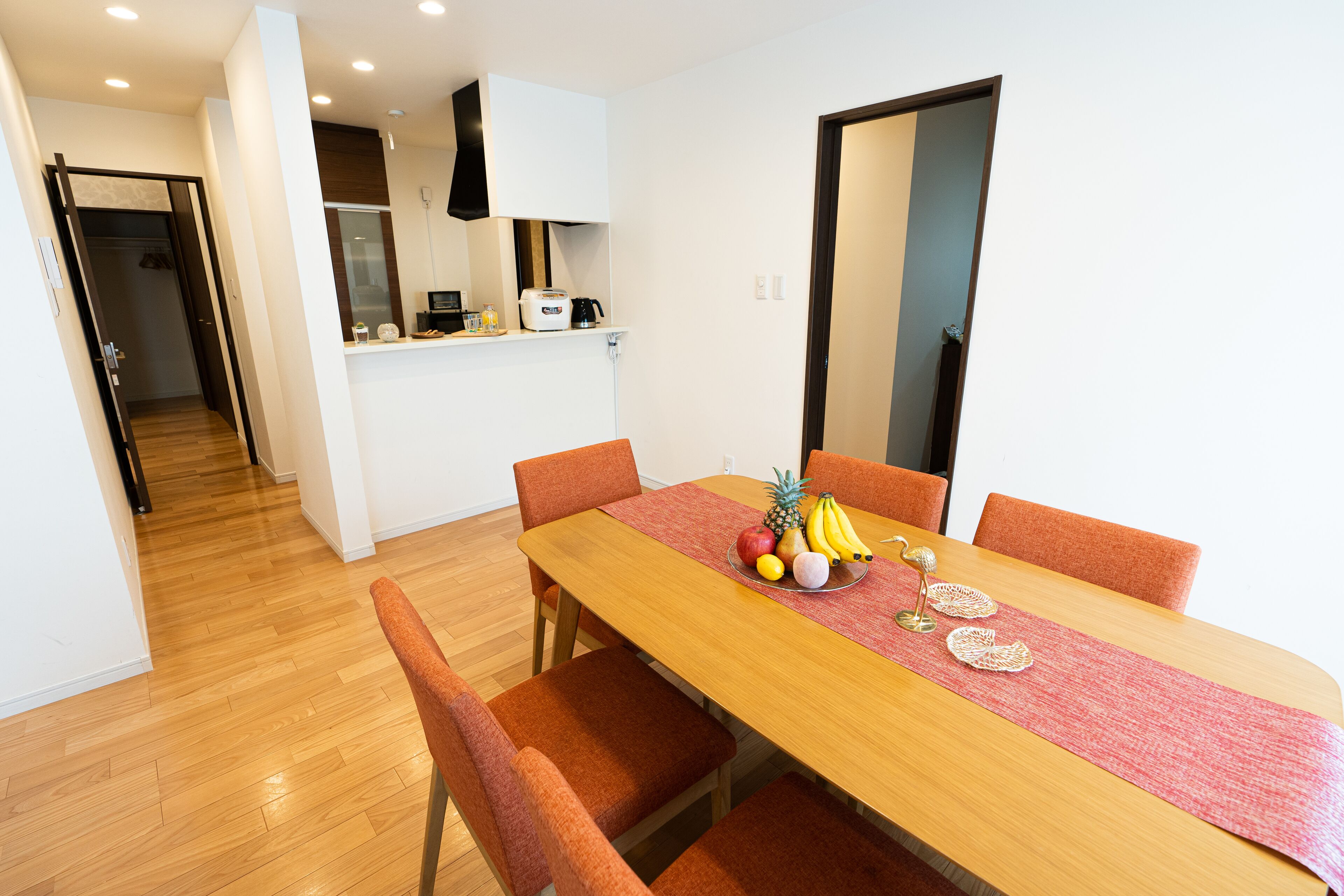A dining area with a wooden table, orange chairs, and a fruit bowl.