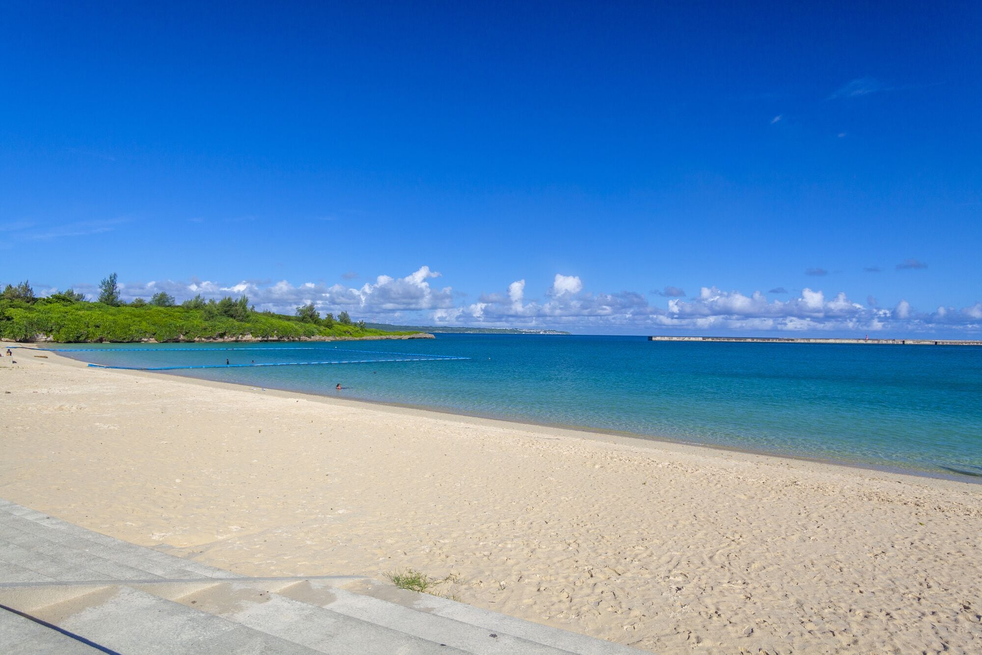 Una platja amb aigua turquesa cristal·lina, sorra daurada i una illa a la distància.