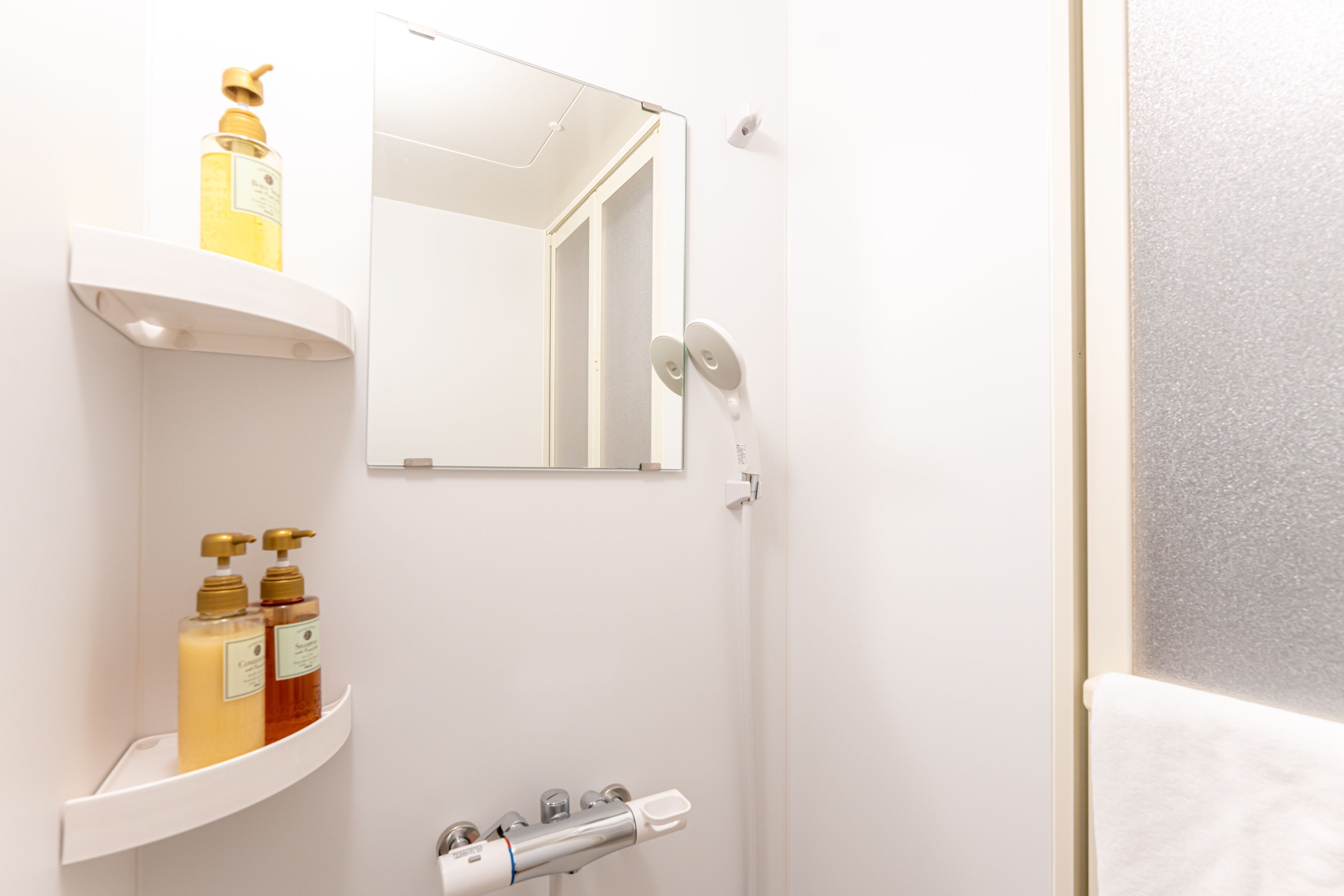 A bathroom with a white sink, a mirror, and two shelves with toiletries.