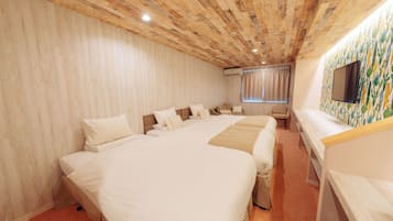 A hotel room with a wooden ceiling, a large bed, a desk, and a TV on the wall.