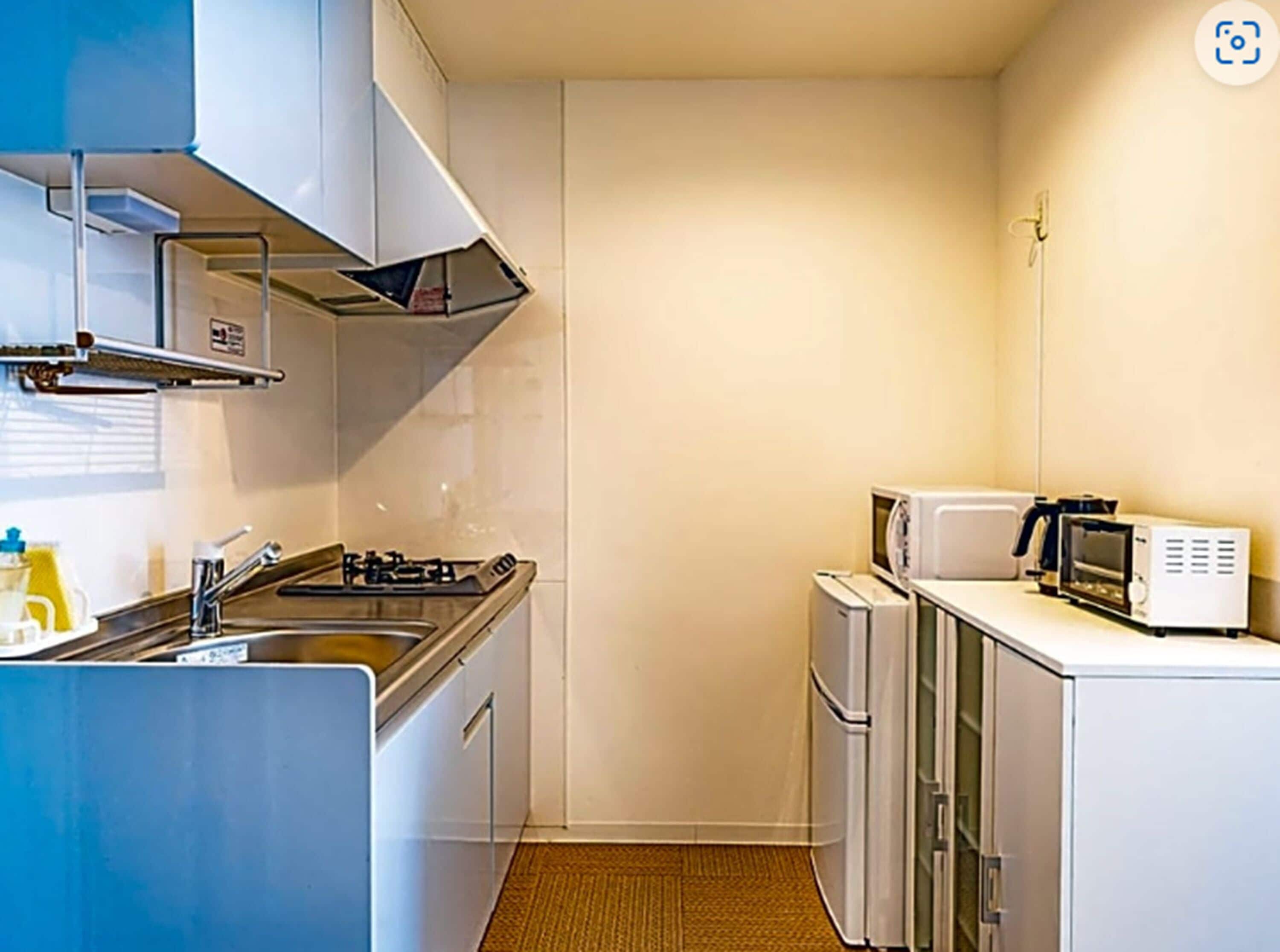 A compact kitchenette with a gas stove, sink, microwave, and small refrigerator.