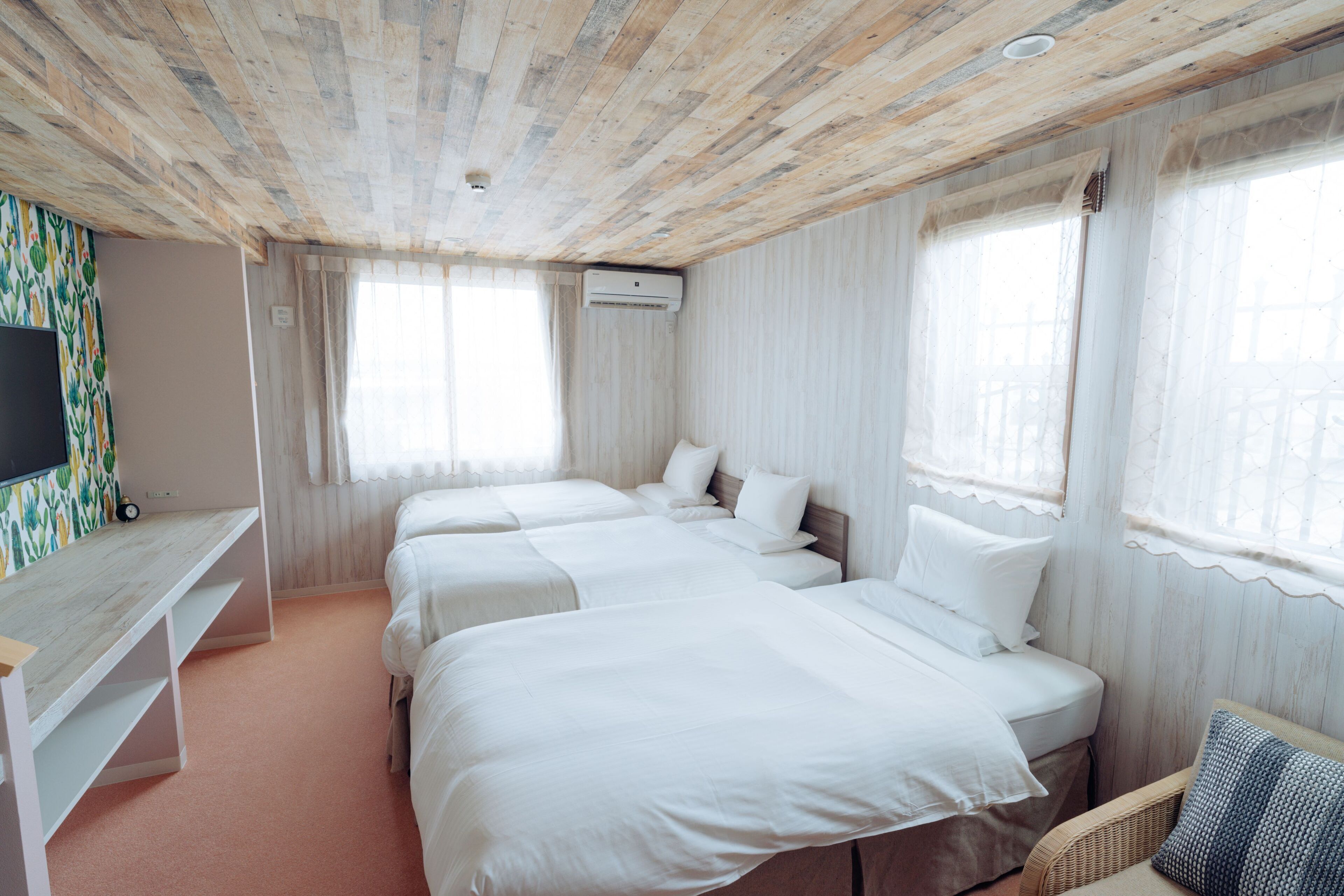 A hotel room with two beds, a TV, and a desk.