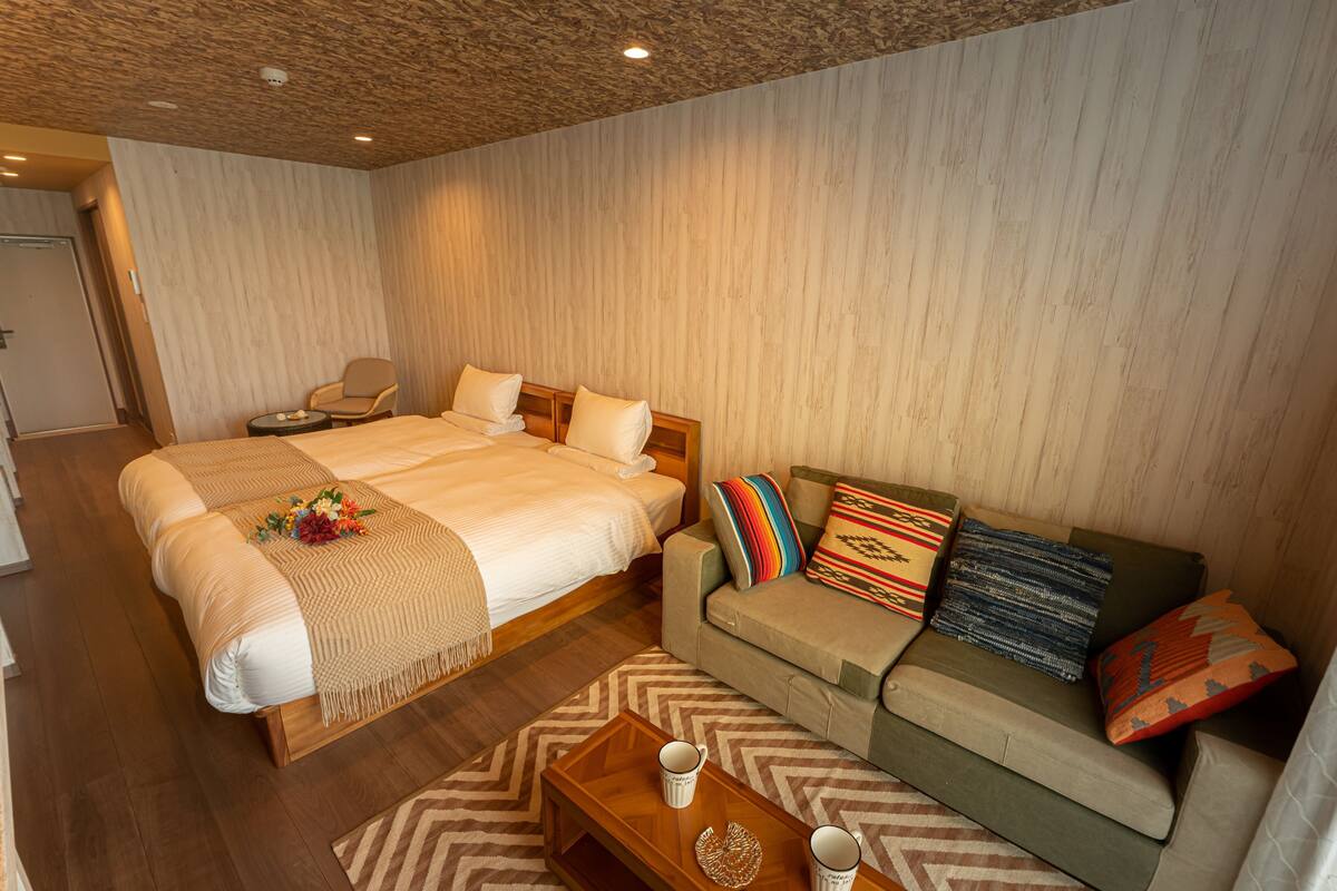 Une chambre d’hôtel avec un grand lit, un canapé, une table basse en bois et une chaise.