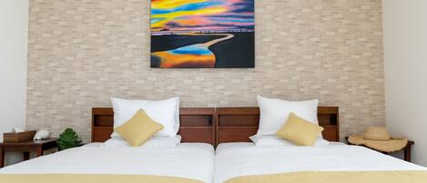 A double bed with white and gold bedding, a wooden headboard, and a wall-mounted painting of a sunset over a river.