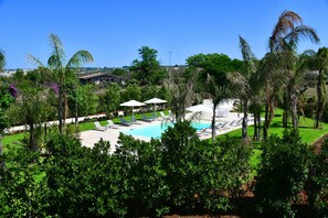 A pool area with lounge chairs and umbrellas, surrounded by palm trees and greenery. - Borgo Fiorito Relais (Parabita)