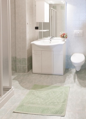Ein Badezimmer mit einem weißen Waschbecken, einer Toilette und einer Duschkabine.