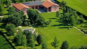 Un grand bâtiment coiffé d’un toit recouvert de tuiles rouges, entouré de pelouses verdoyantes et d’arbres.