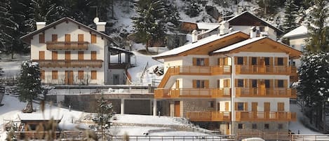 Un hotel de varios pisos con balcones, situado en una zona montañosa nevada.