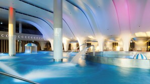 Una piscina interior con diseño moderno, que cuenta con un techo curvo y varias zonas de estar.