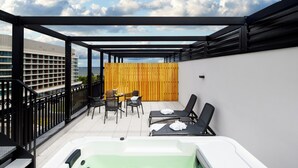 Terraza en la azotea con jacuzzi, sillones de descanso y zona de comedor con sillas y mesa.