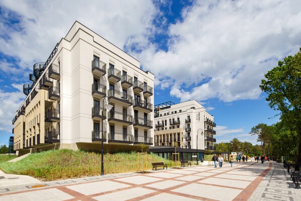 A modern apartment building with multiple balconies and a spacious outdoor area with benches.