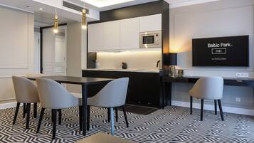 Cozinha moderna com micro-ondas, área de jantar com cadeiras e uma TV de tela plana exibindo 'Baltic Park by ZDROJOWA'.