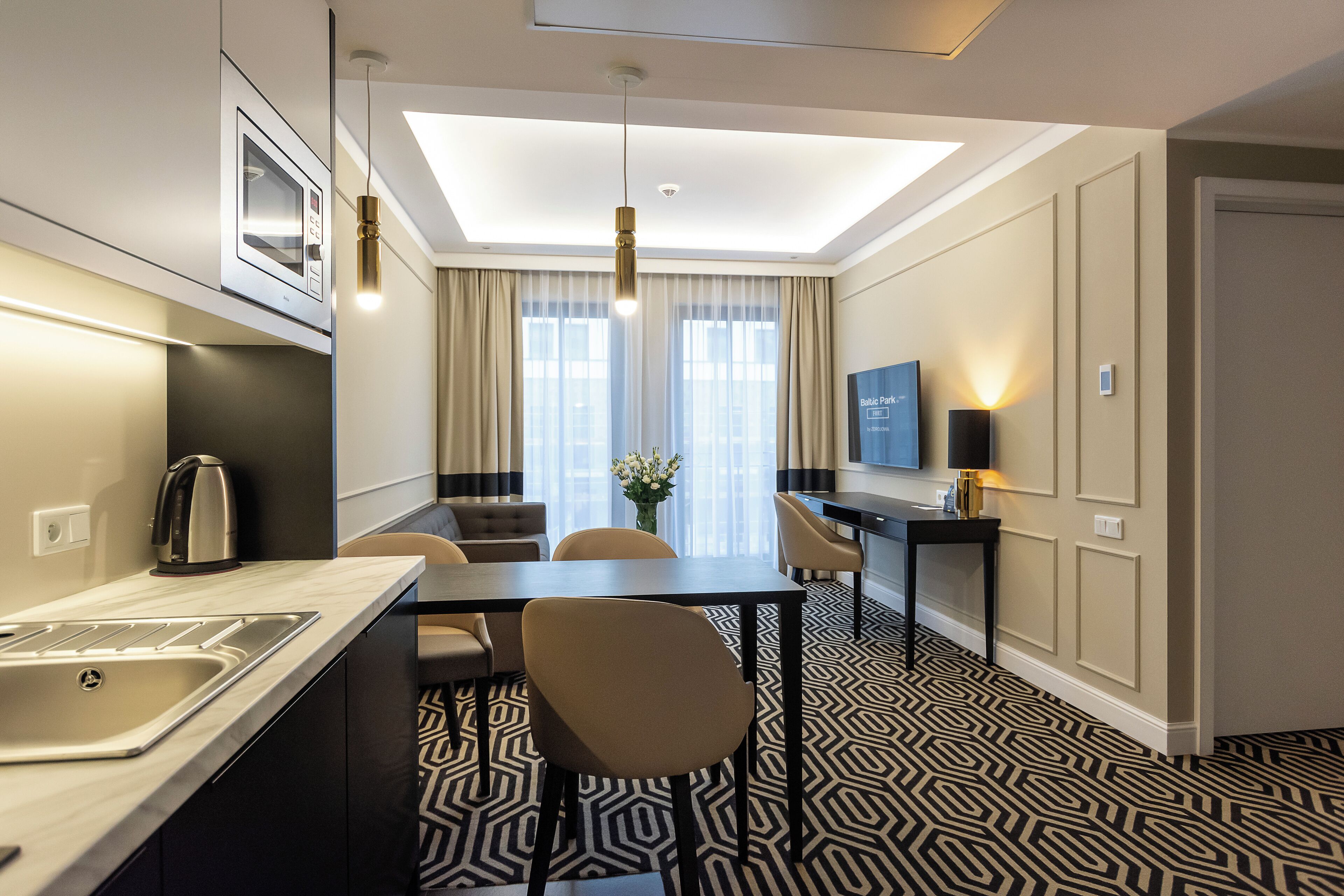 Een moderne hotelkamer met een keukenhoek, een eettafel en een zithoek.