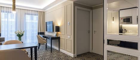 Une chambre d’hôtel dotée d’un coin repas, d’un téléviseur à écran plat, d’un four à micro-ondes et d’un grand miroir.