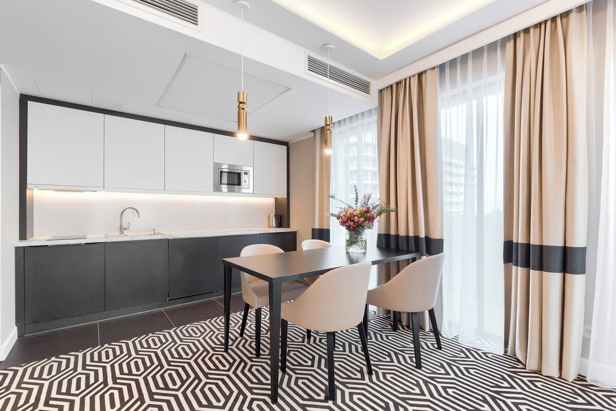 A modern kitchen with dark cabinets, a stainless steel microwave, and pendant lighting.