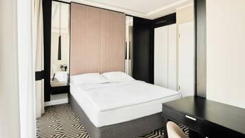 A modern hotel room with a large bed, a desk, and a mirror.