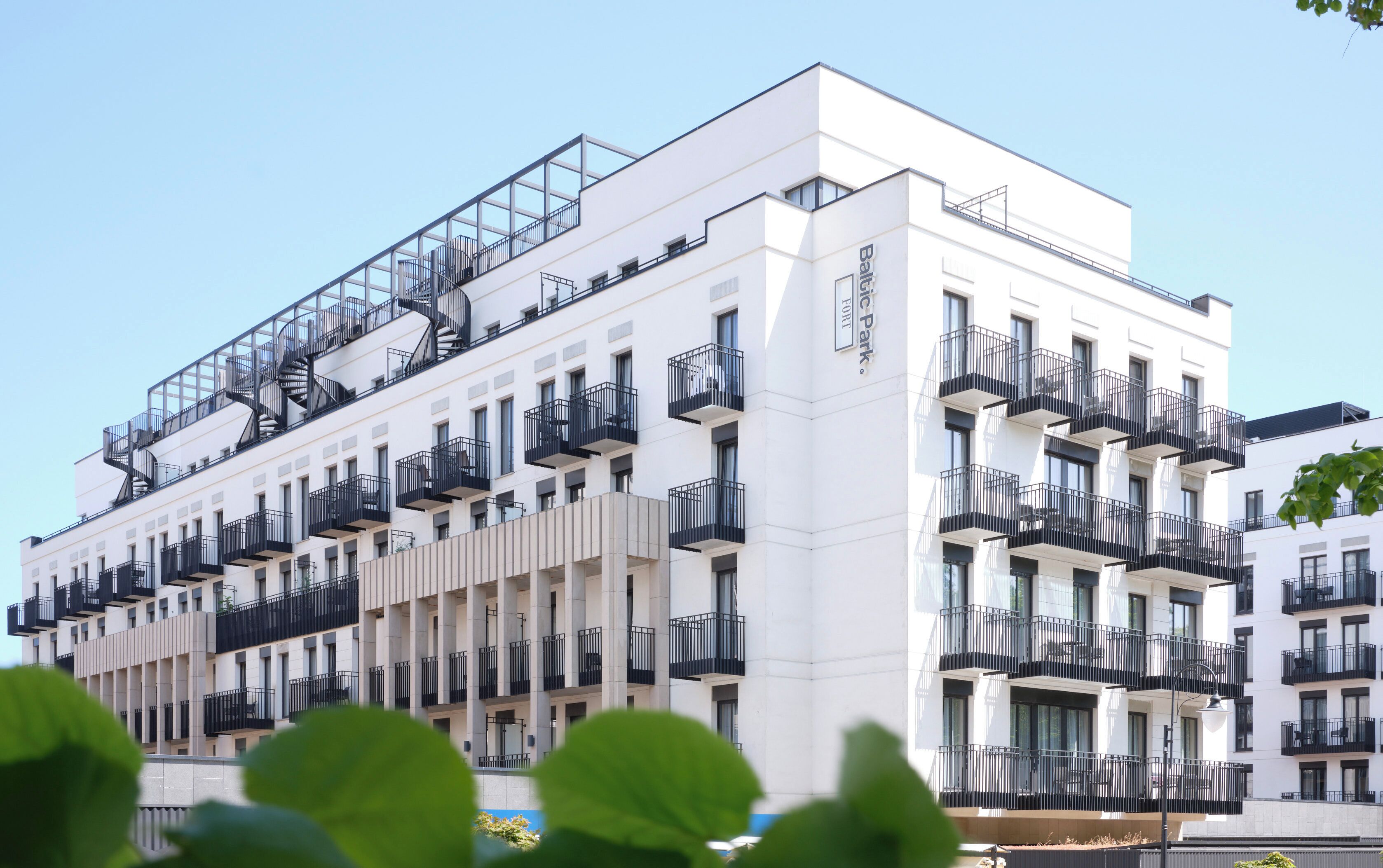 A multi-story building with balconies, a fire escape, and a sign indicating it's a hotel.