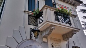 A building with a white facade, a balcony with black railings, and a small window with shutters. - Relais Toti B&B (Mogliano Veneto)