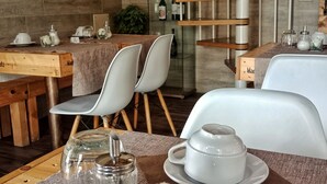 A modern dining area with wooden tables, white chairs, and a glass display cabinet with wine bottles. - Relais Toti B&B (Mogliano Veneto)