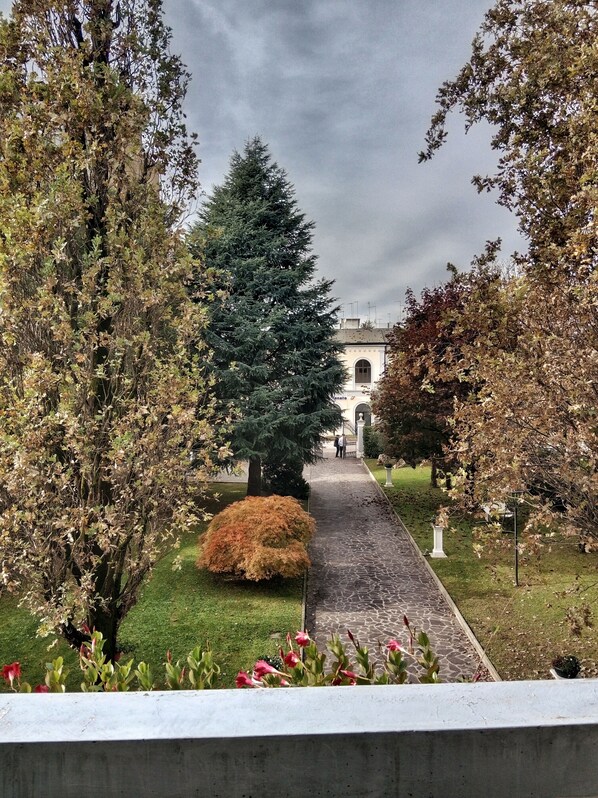 A pathway leading to a building with a classical architectural style, surrounded by trees and shrubs. - Relais Toti B&B (Mogliano Veneto)