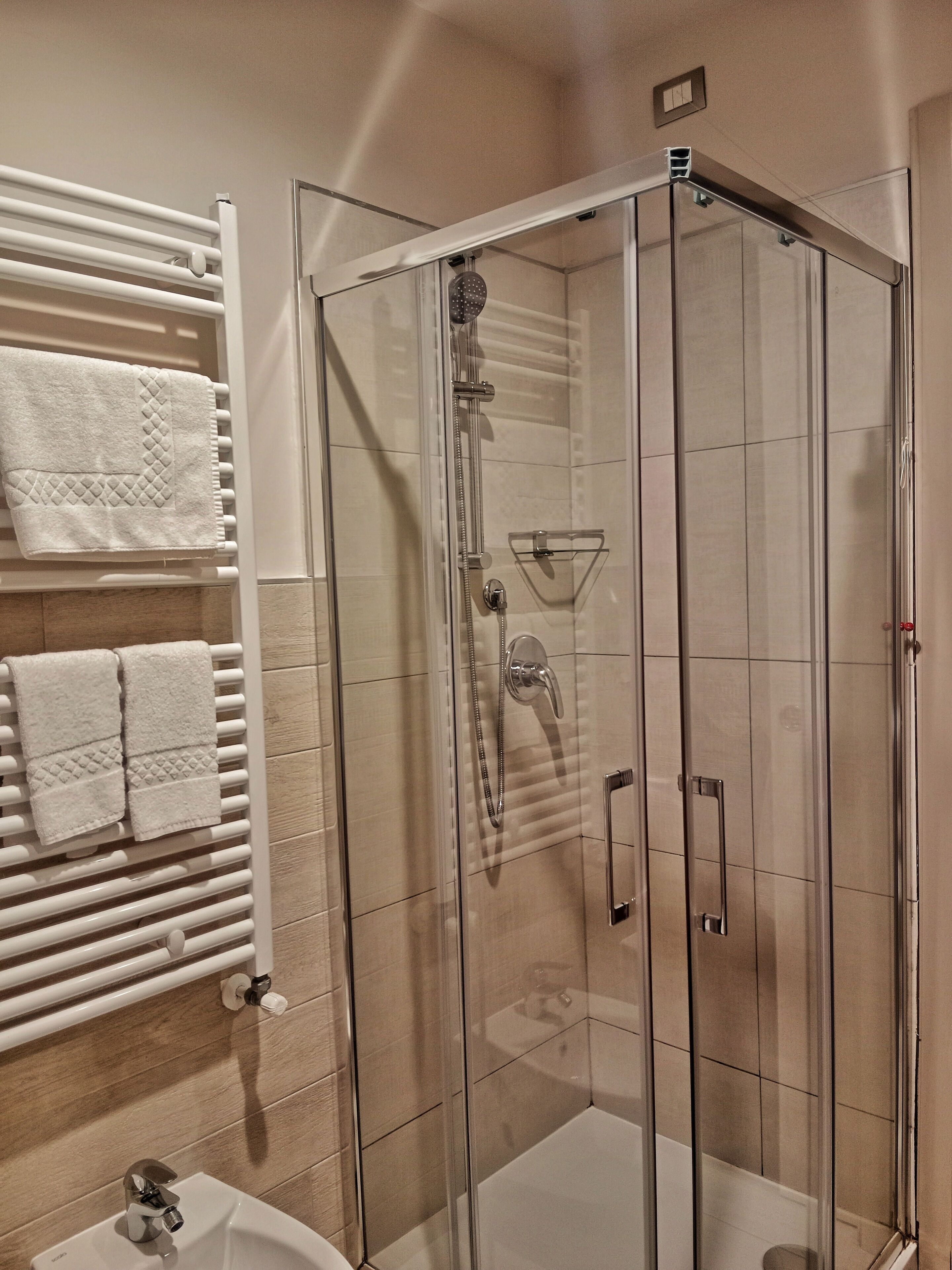 Eine begegnete Dusche mit Handbrause und am Wand montiertem Wasserhahn.