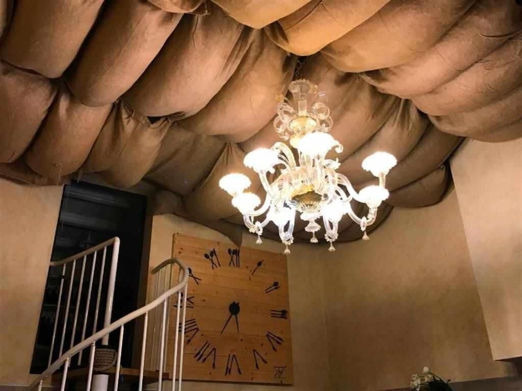 Ein Kronleuchter mit mehreren Lichtern, eine Holz-Wand-Uhr und eine Treppe.