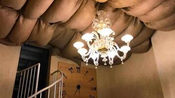 Ein Kronleuchter mit mehreren Lichtern, eine Holz-Wand-Uhr und eine Treppe.