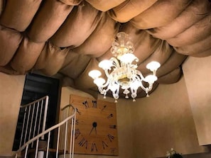 A chandelier with multiple lights, a wooden wall clock, and a staircase. - Relais Toti B&B (Mogliano Veneto)