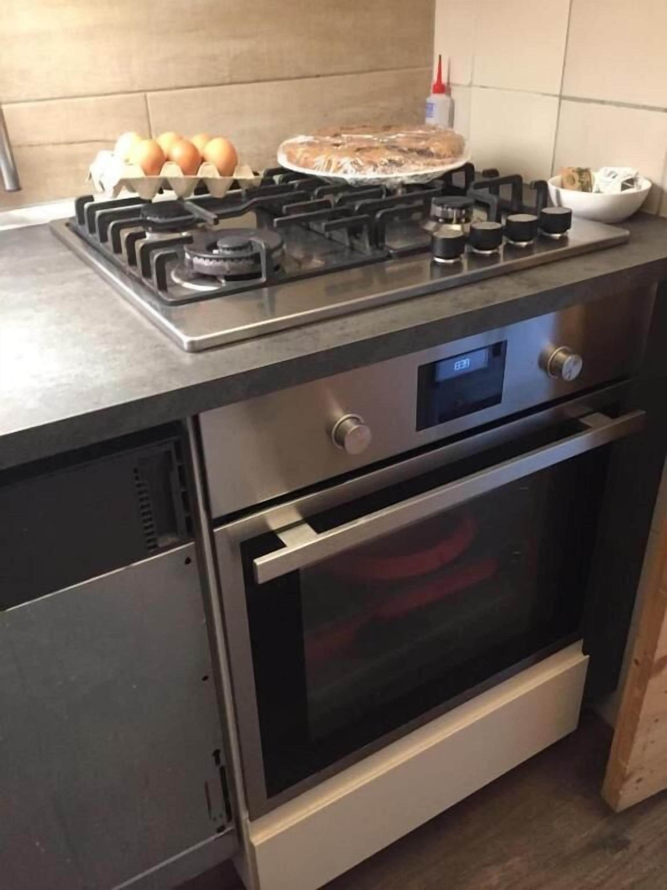 Une cuisine équipée d’une cuisinière à gaz, d’un four et d’un écran numérique.