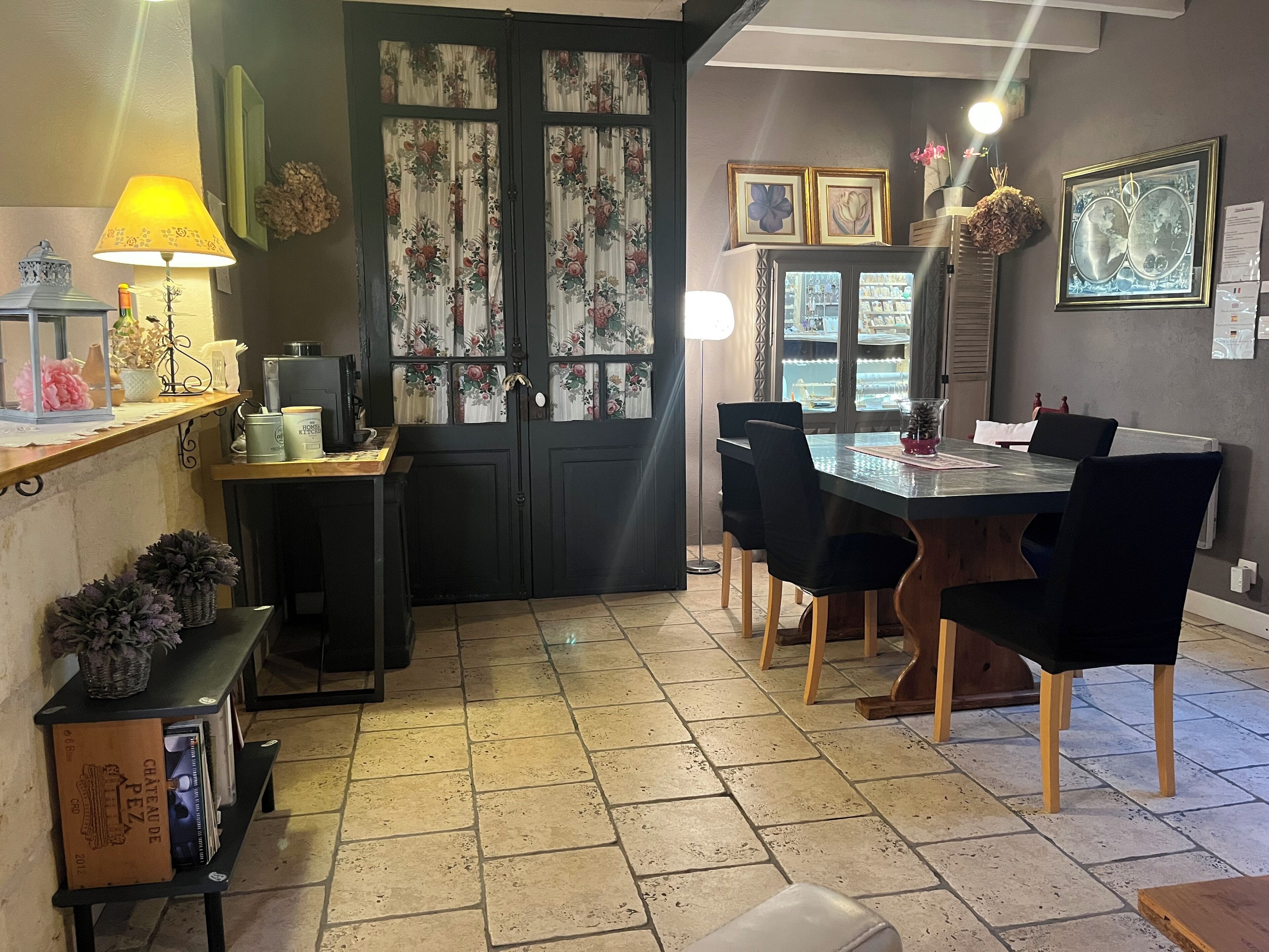 A dining area with a table, chairs, and a black door with floral curtains.