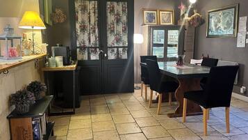 A dining area with a table, chairs, and a black door with floral curtains.