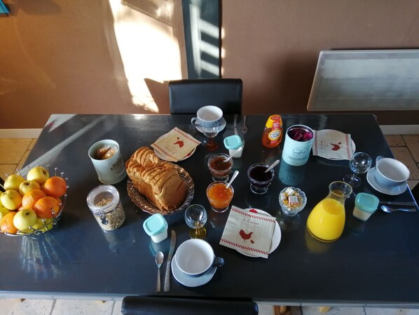 Una mesa de desayuno con frutas, pan, café y salsas.