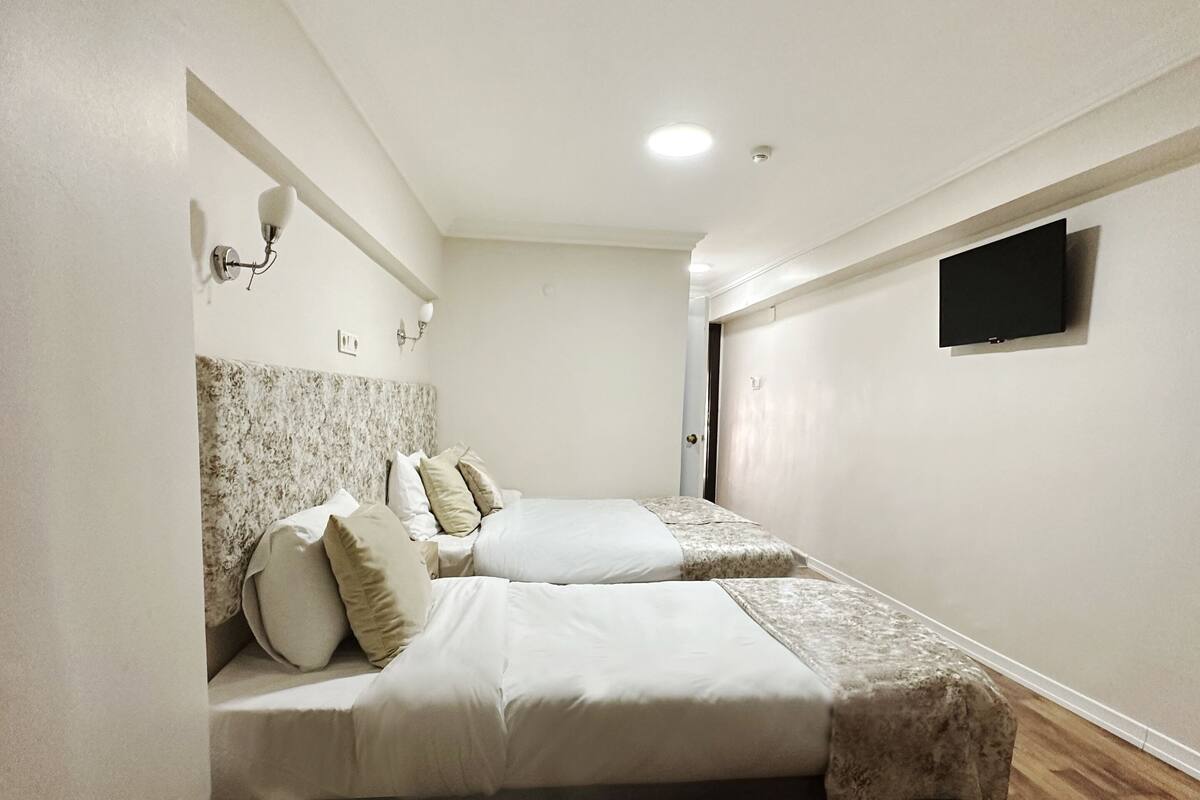 Une chambre à coucher avec un lit, un téléviseur fixé au mur et un plancher en bois.
