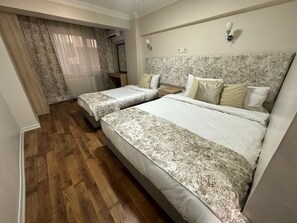 A hotel room with two beds, wooden flooring, a marble headboard, and a window with curtains. - Hotel Antik Ipek (Istanbul)