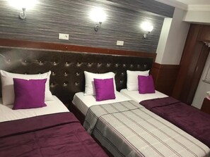 A hotel room with a tufted headboard, three beds with purple and white bedding, and a striped bed runner. - Hotel Antik Ipek (Istanbul)