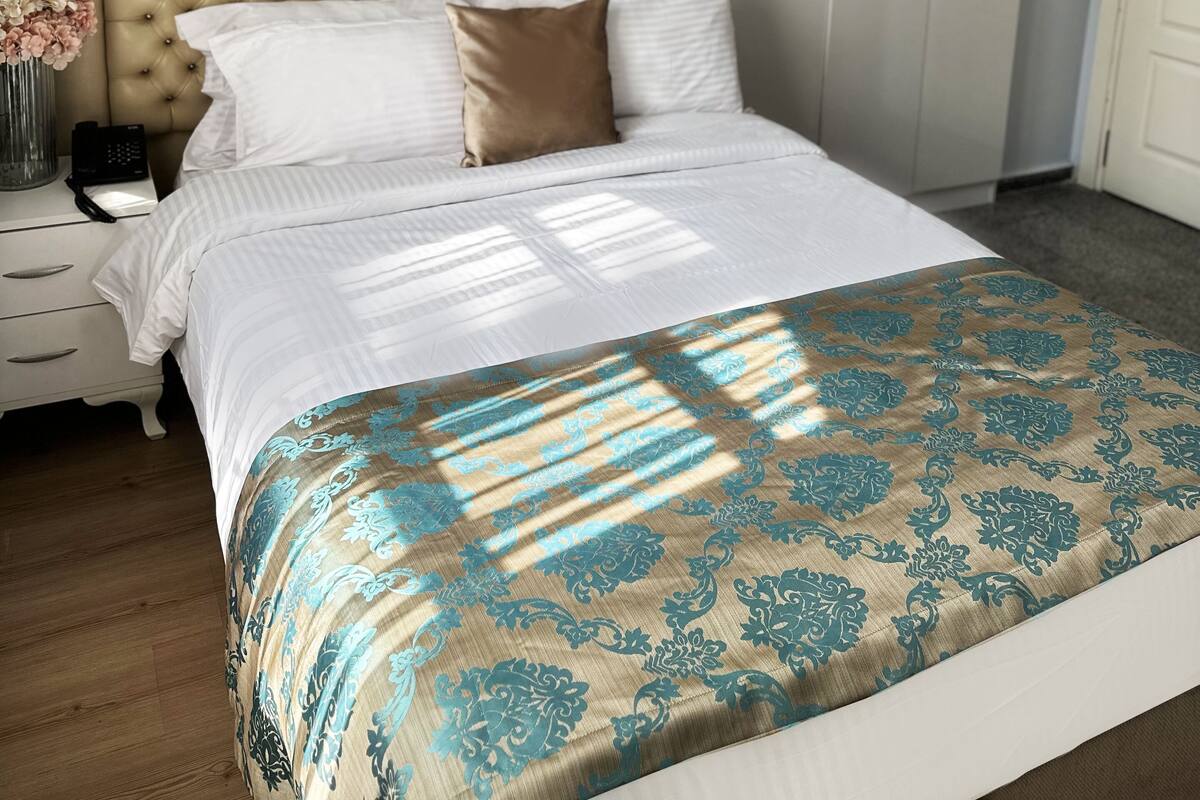 Une chambre à coucher comprenant un lit, une table de chevet, une armoire et deux appliques murales.