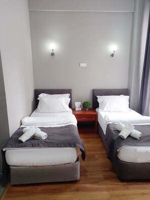 A hotel room with two beds, each with white linens and gray bedding. There are wall-mounted light fixtures and a small bedside table with a plant. - Hotel Antik Ipek (Istanbul)