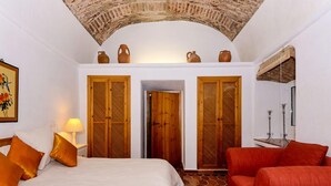 Une pièce avec un lit, un canapé rouge et deux portes en bois.