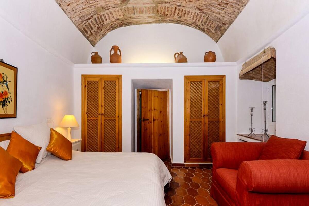 Une pièce avec un lit, un canapé rouge et deux portes en bois.