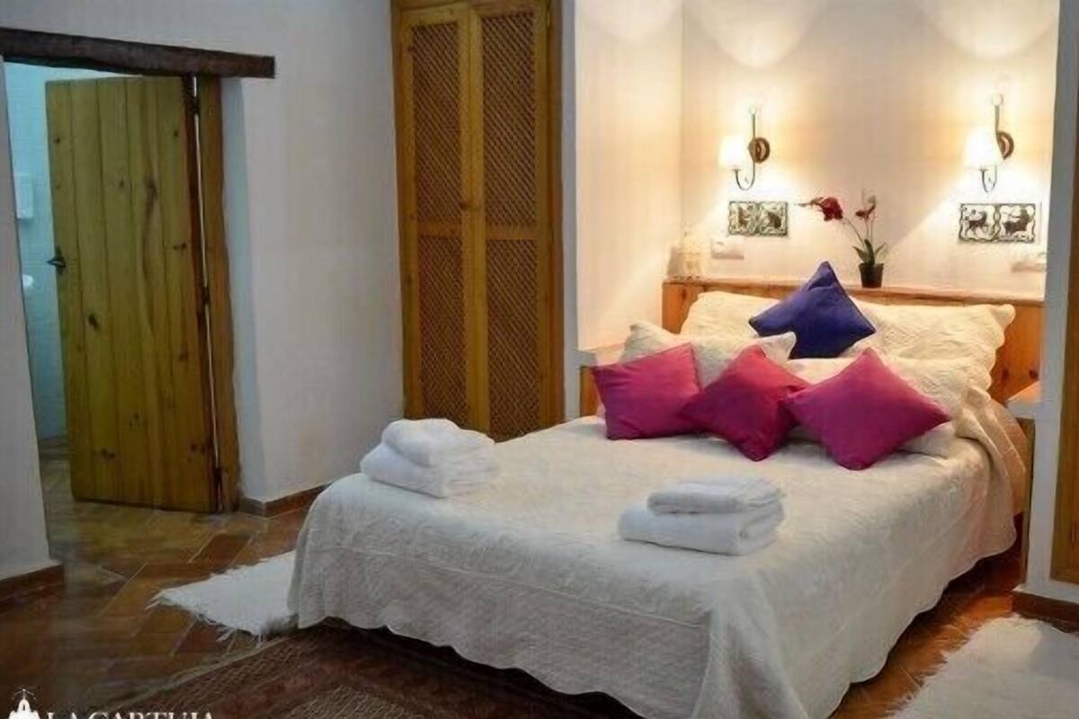 Un lit bien fait, avec du linge de lit blanc et plusieurs oreillers de différentes couleurs.