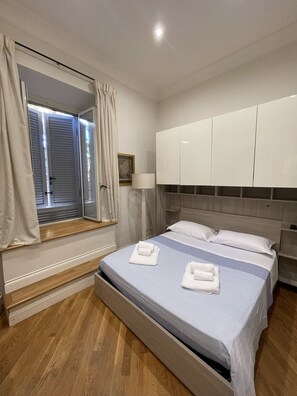 Une chambre à coucher avec un lit, une fenêtre avec des rideaux, une lampe de chevet et une armoire.