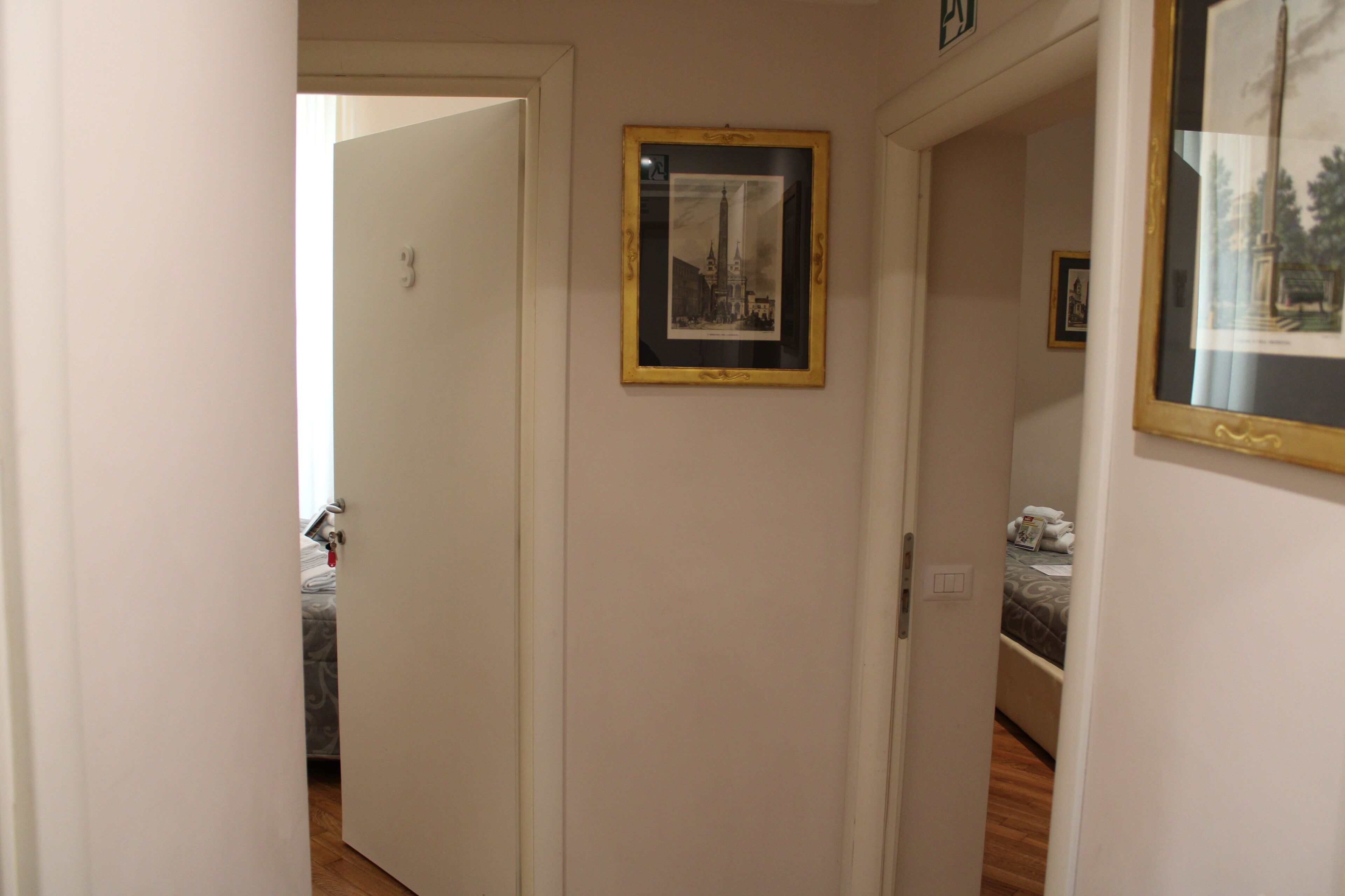 A hallway with a door leading to a bedroom. There is a framed picture on the wall.