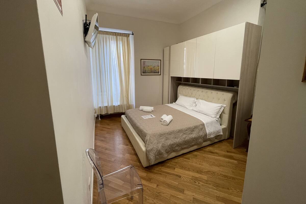 Une chambre d’hôtel avec un lit, une chaise, une armoire et un tableau au mur.