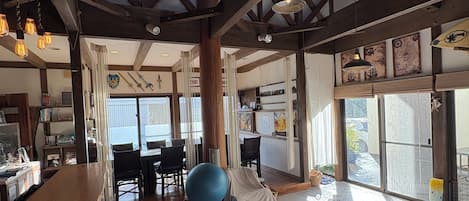 A spacious room with a high ceiling, wooden beams, a long bar with stools, and a large exercise ball.