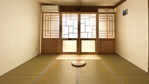 Una habitación japonesa tradicional con suelo de tatami, puertas correderas y un futón en el centro.