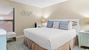 A bedroom with a bed, bedside tables, a lamp, and a wall decoration.