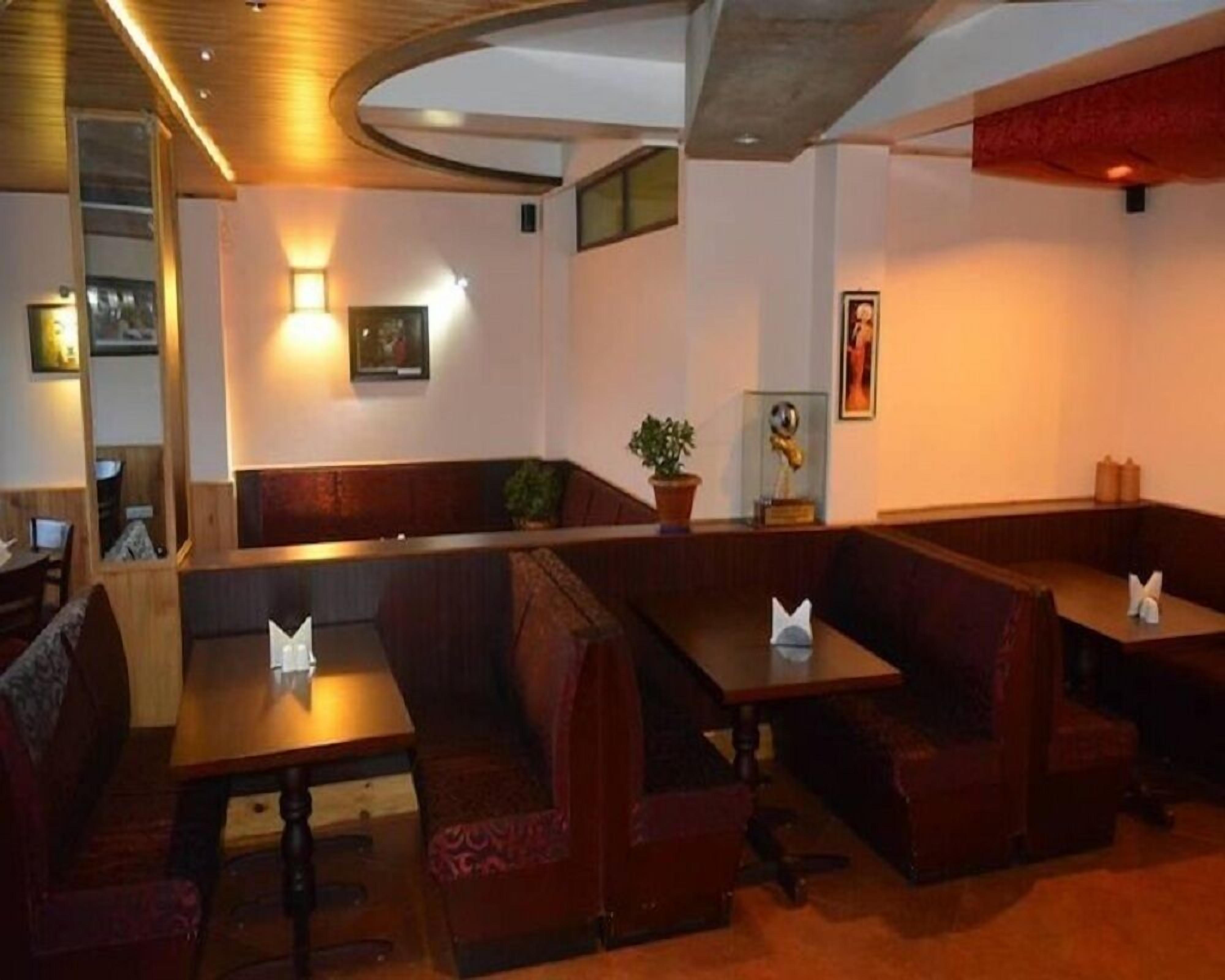 A restaurant with booths and tables, wooden ceiling, and wall-mounted lighting.